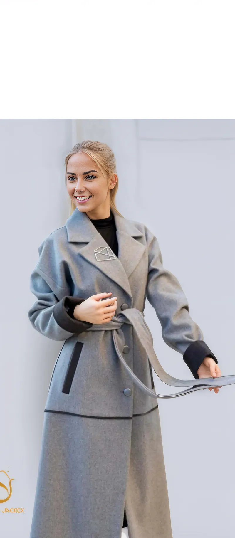 Stylish woman modeling a long, gray winter coat with a belt, perfect for modern women's winter fashion.